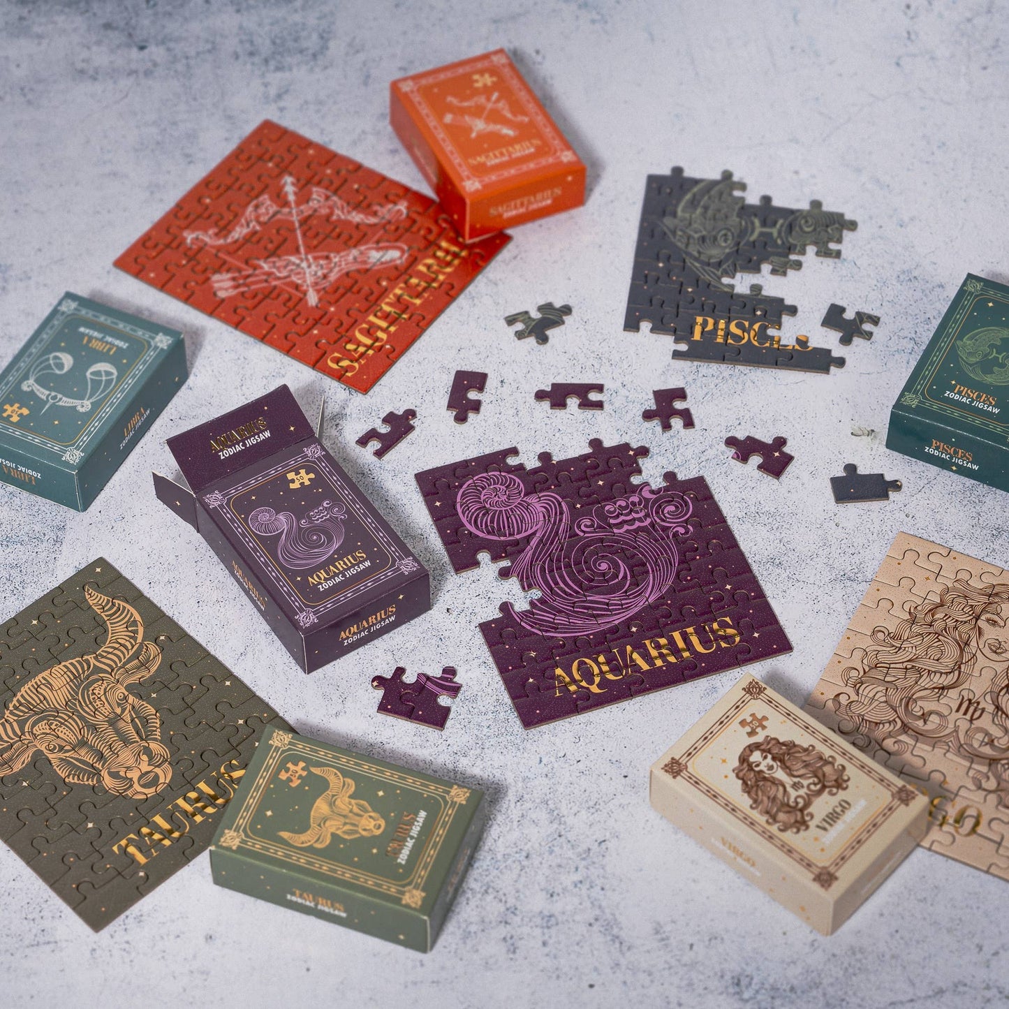 Zodiac-themed puzzle boxes and pieces on a textured surface