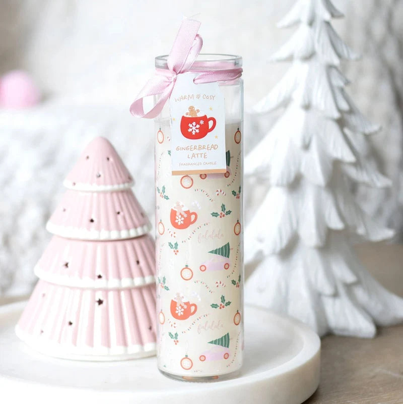 A tall glass jar candle with a pink ribbon bow and a decorative label reading Gingerbread Latte, styled on a white tray beside pink and white Christmas tree ornaments.
